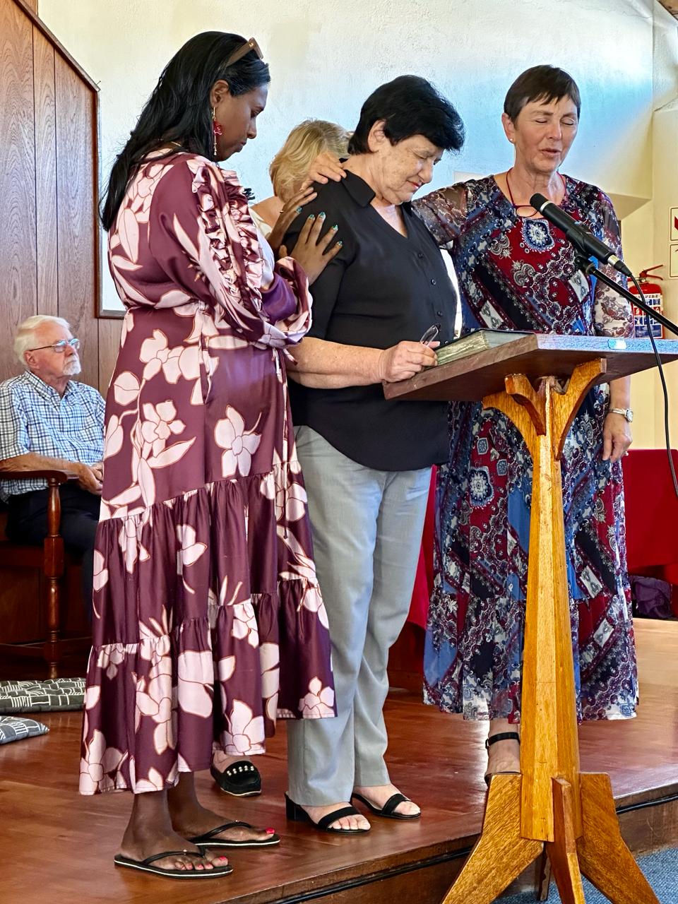 Women praying over the guest preacher: Edith Sher